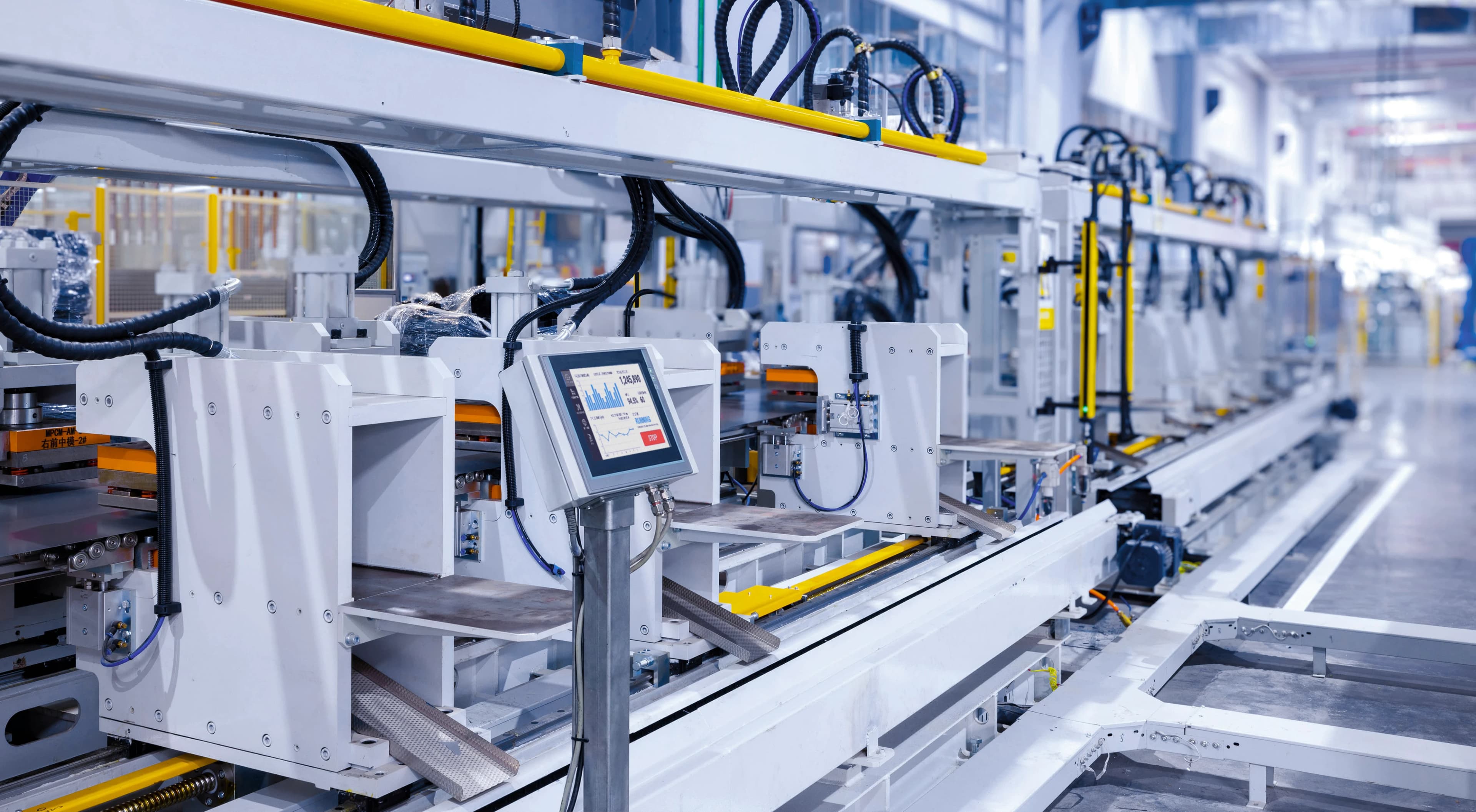 An interface panel connected to a large industrial machine in a clean factory setting